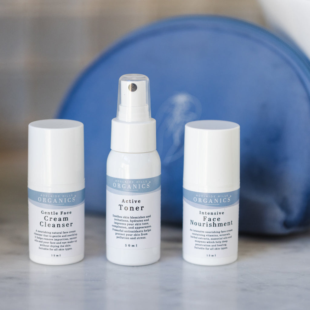 Three skincare bottles with a blue pouch on a marble surface