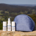 Set of skincare products and a blue pouch on a rock with a scenic background